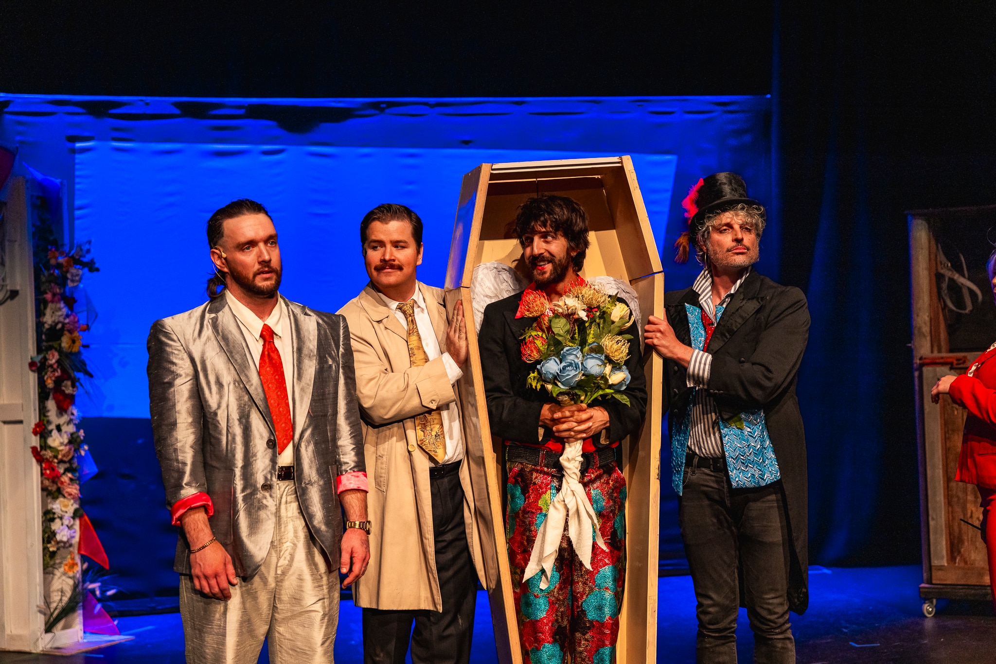 Four people standing next to each other, dressed up on stage.
