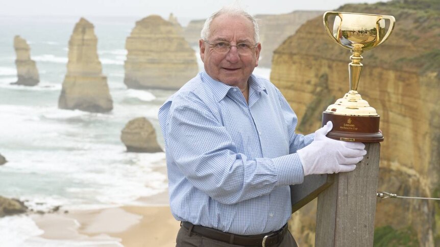 Mick Robins, holding the Melbourne cup at a beach, years after his famous win in 1968