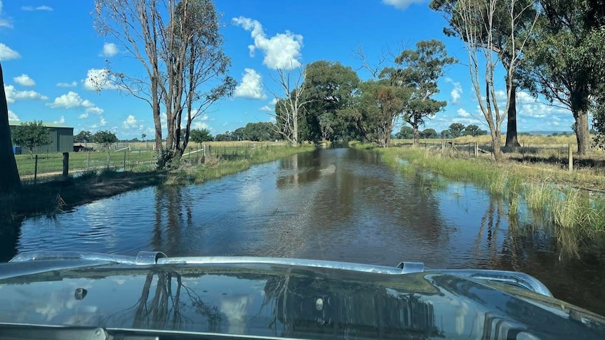A flood impacted road viewed from inside a car