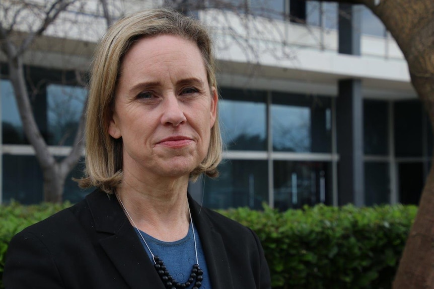 Simone McGurk standing outside with an office building and trees in the background.