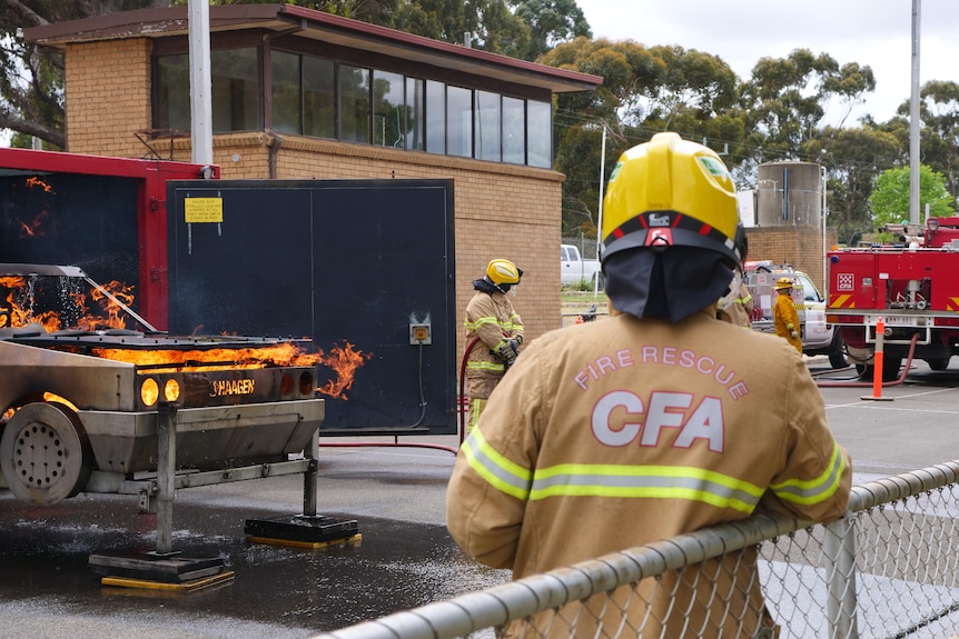 a man in a CFA jacket watches a fire rescue