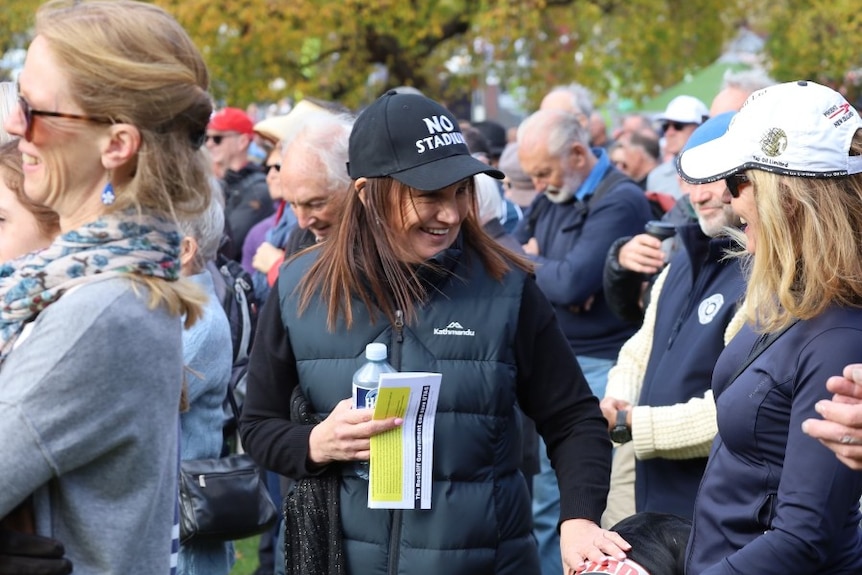 A woman in a baseball cap talks to a woman in a crowd