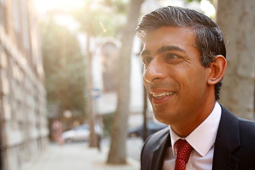 Rishi Sunak smiling as the sun shines on his face 