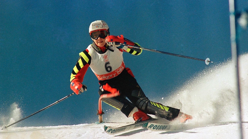 Blanca Fernandez Ochoa skis down a hill with her poles splayed out on each side and a slalom pole being bent over under her shin