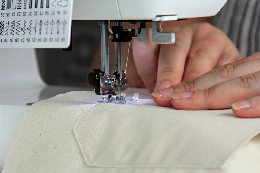Close up of fingers sewing with a sewing machine