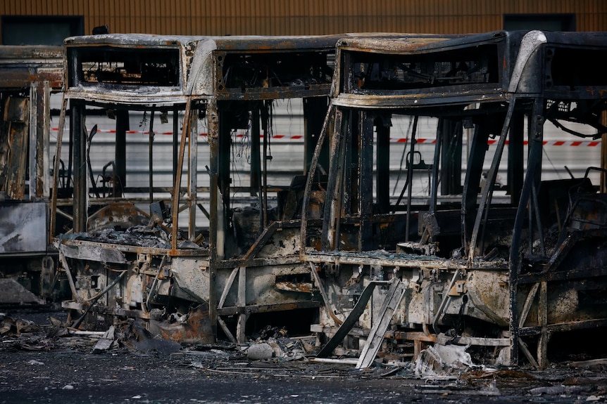 View of burnt buses at a depot. 