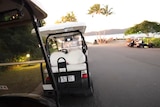 Looking down a roadway through the passenger seat of a golf buggy on a resort island
