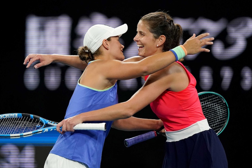 Two female tennis players hug after winning a doubles match at the Australian Open.