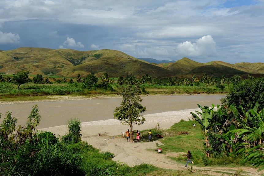 A muddy river with people standing along its edge