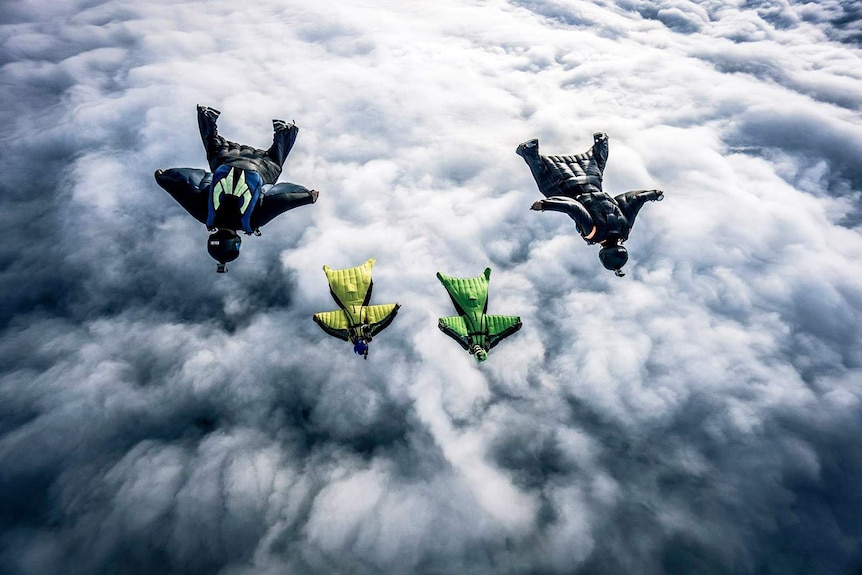 Four wingsuit flyers above the clouds