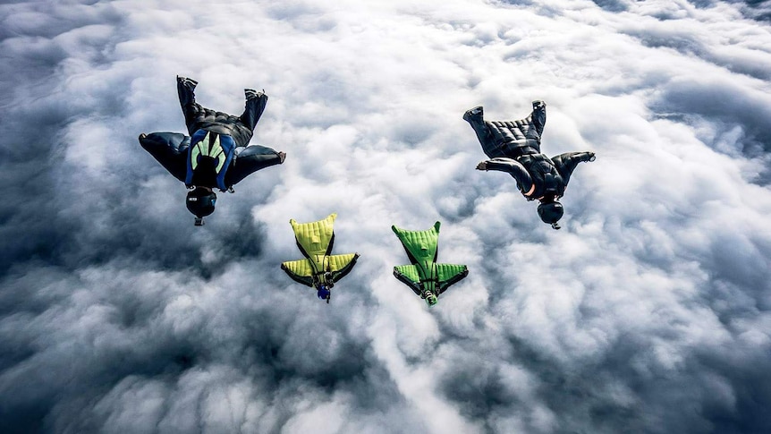 Four wingsuit flyers above the clouds
