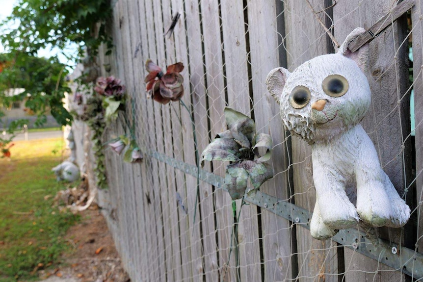 Stuffed toy and flowers hanging on fence at Murray Street memorial