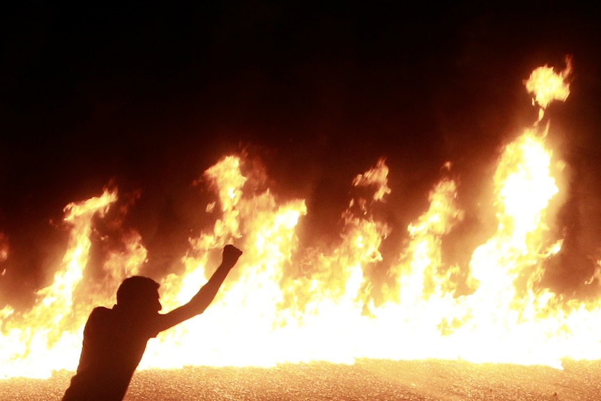 A protester stands near a line of fire during a demonstration in Cairo