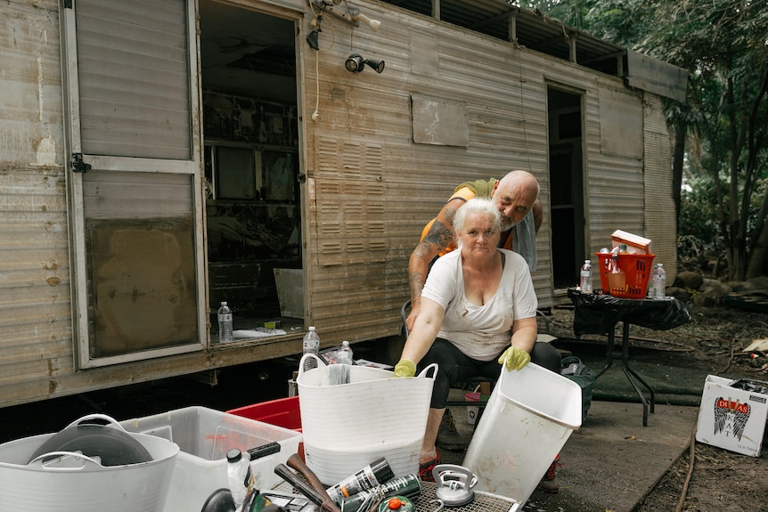 An older woman with two buckets is embraced from behind by Daryl