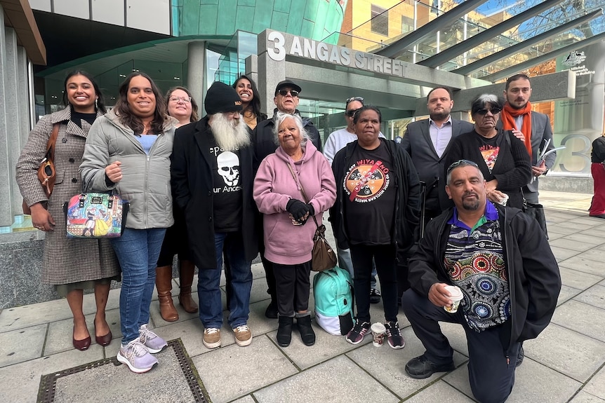 Thirteen people from the Barngarla community stand in front of a court building smiling.