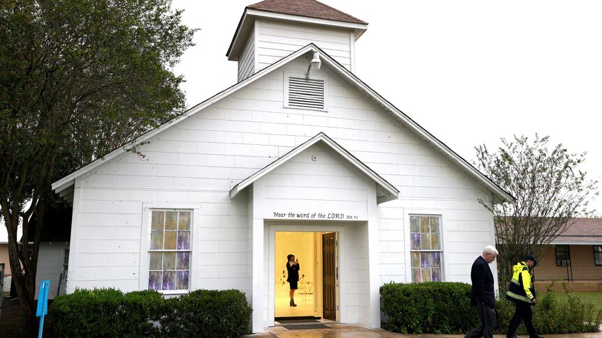 A woman is inside a church seen through the door.