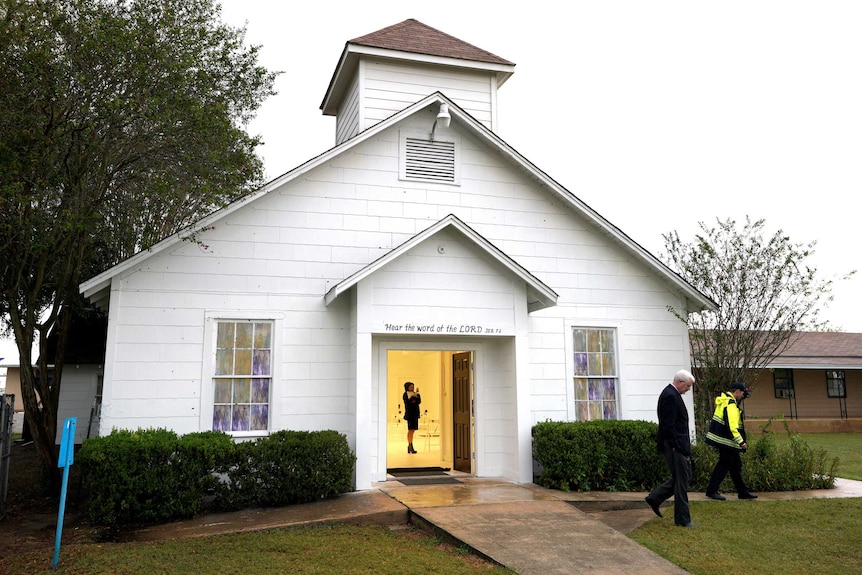 A woman is inside a church seen through the door.