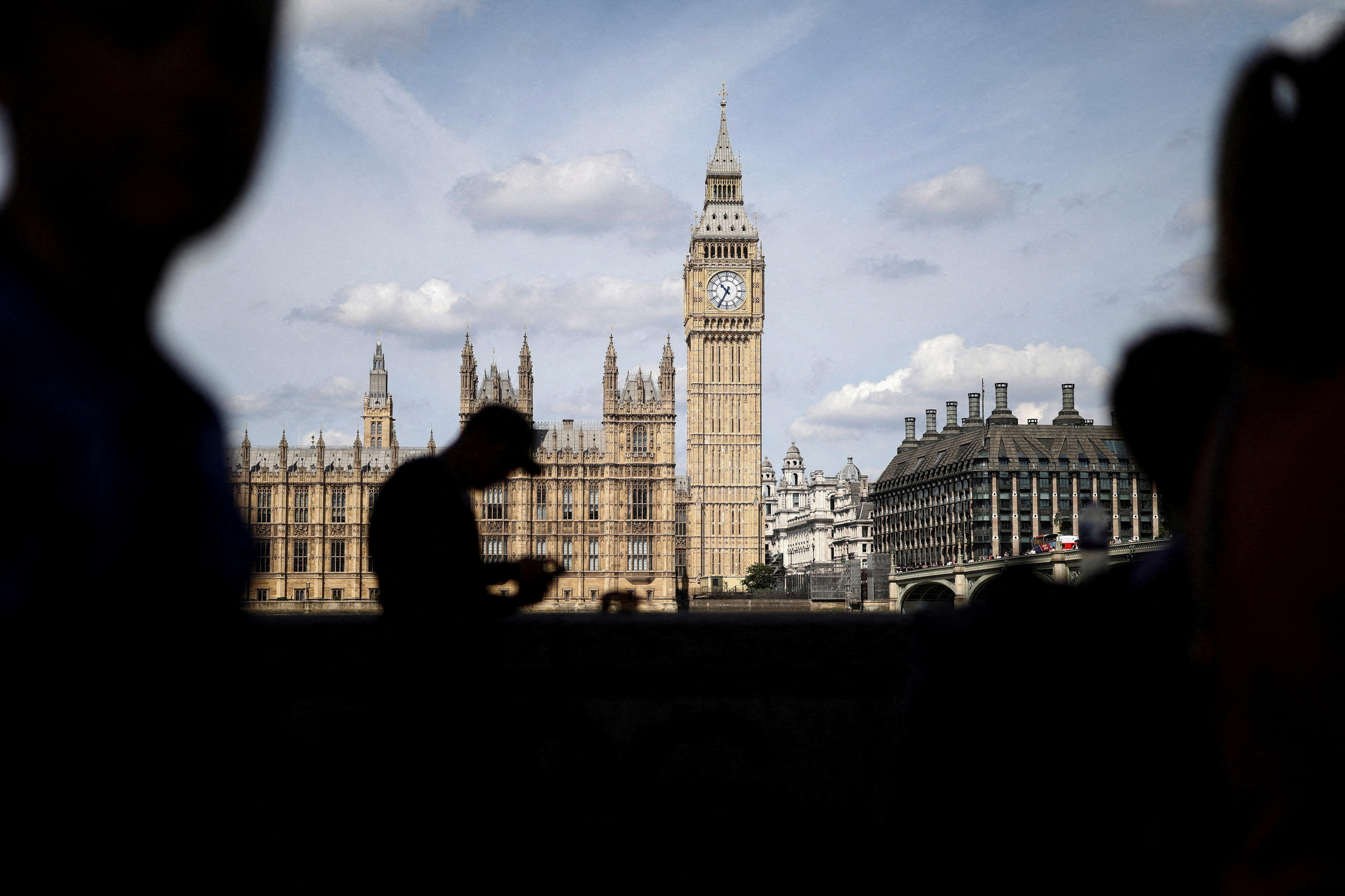 The UK Houses of Parliament and Big Ben as seen from across the River Thames, with a man's silhouette in the foreground. 