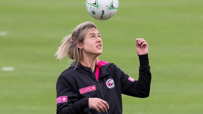 Ellyse Perry wears her magenta and black Sixers kit as she heads a soccer ball