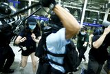 A police officer swings a baton at anti-government protesters at an airport in Hong Kong.