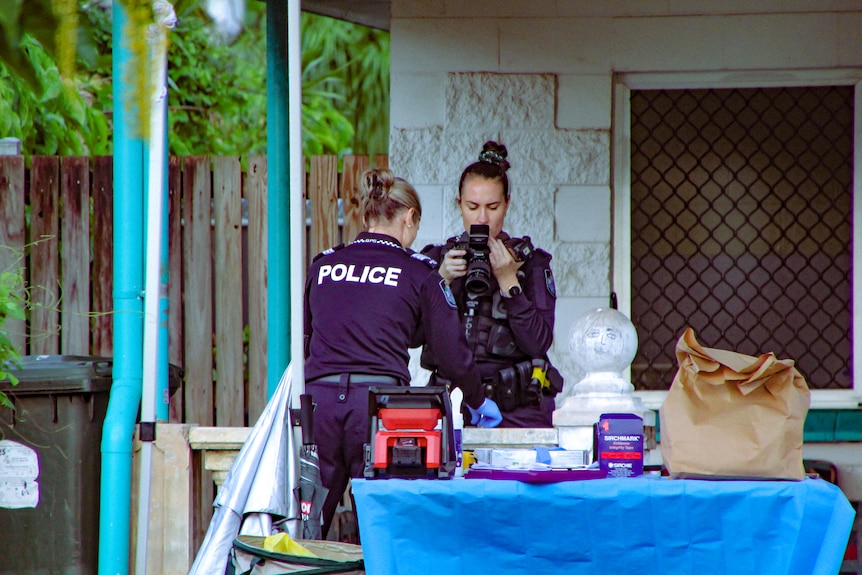 Police investigators photograph a crime scene at a single-story home.