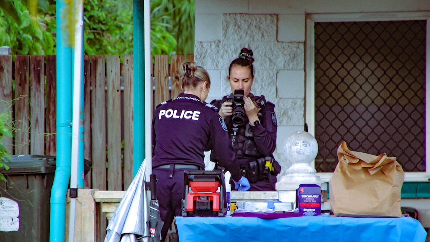 Police investigators photograph a crime scene at a single-storey home.