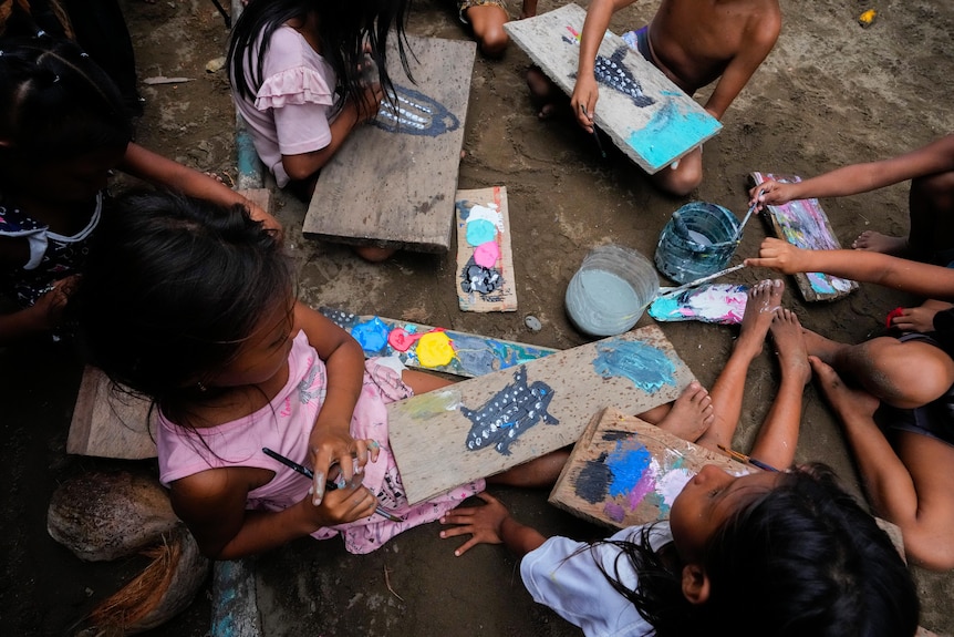 Children paint blocks of wood with images of leatherback turtles