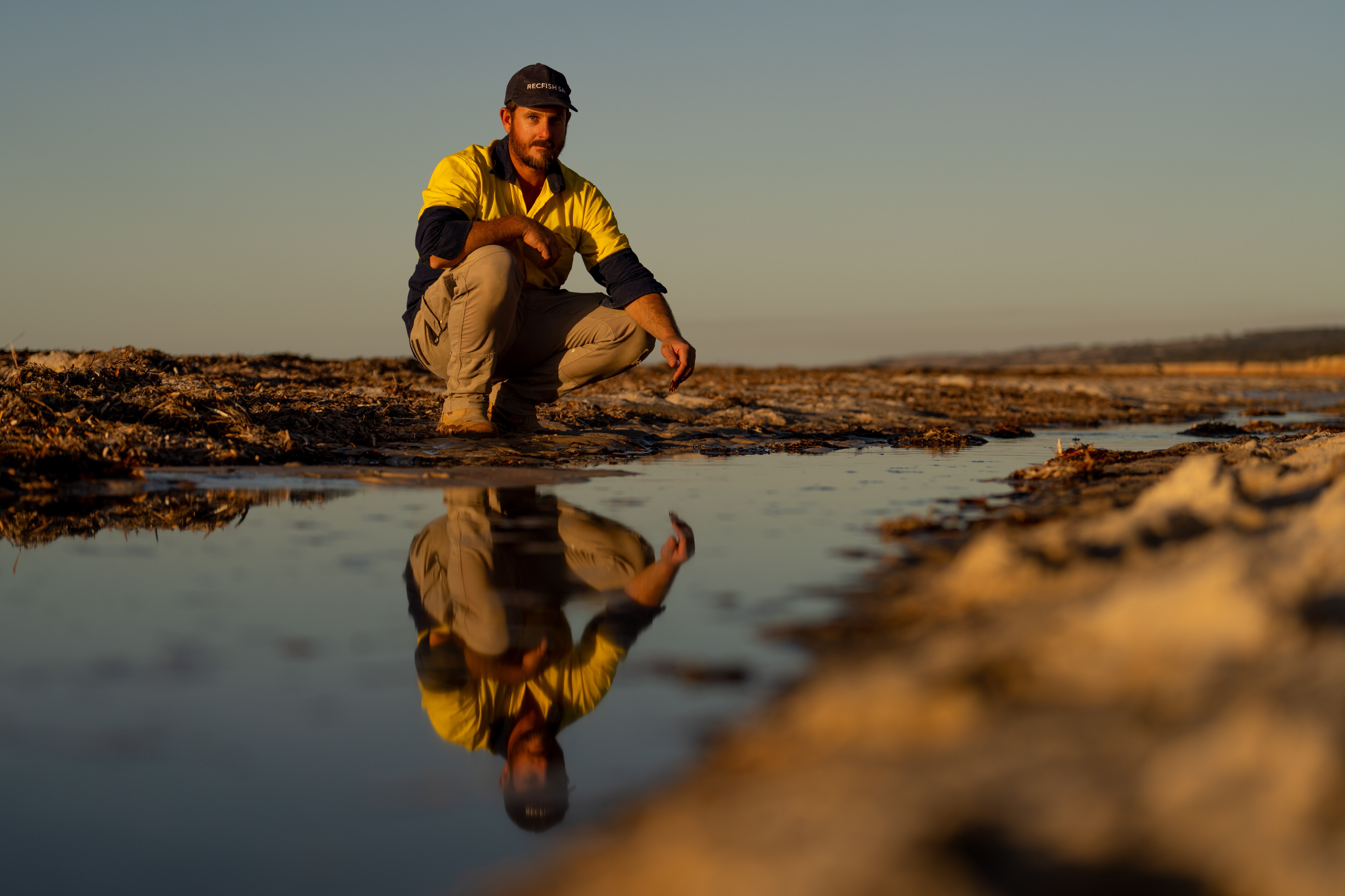 Un hombre arrodillado sobre aguas poco profundas.