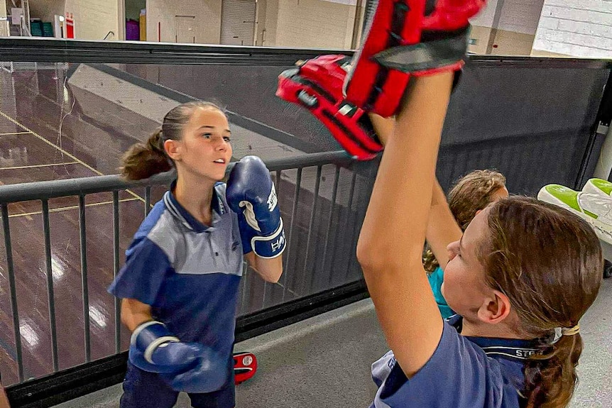 A school student uppercutting a boxing training pad.