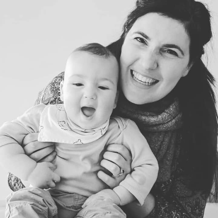 Black and white photo of woman grinning as she holds a happy baby