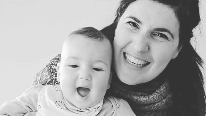 Black and white photo of woman grinning as she holds a happy baby