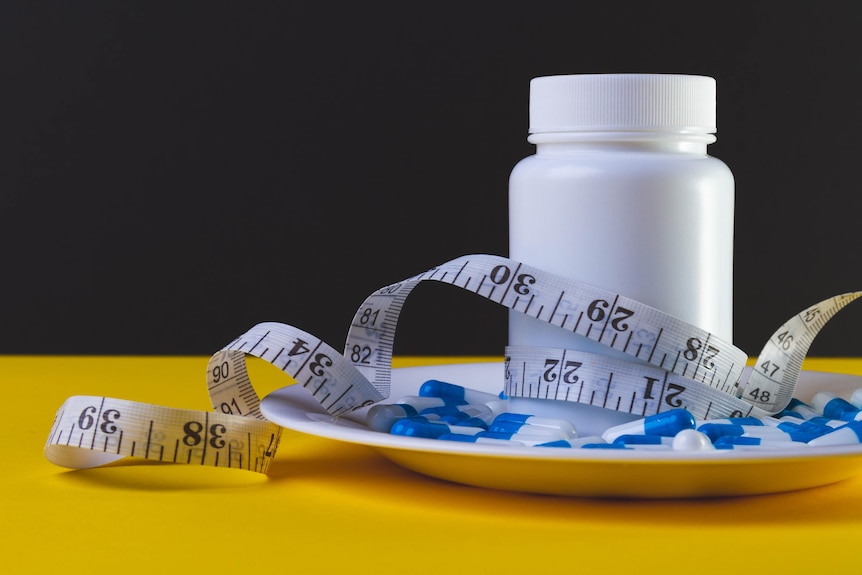 white pill container on a plate with pills and tape measure