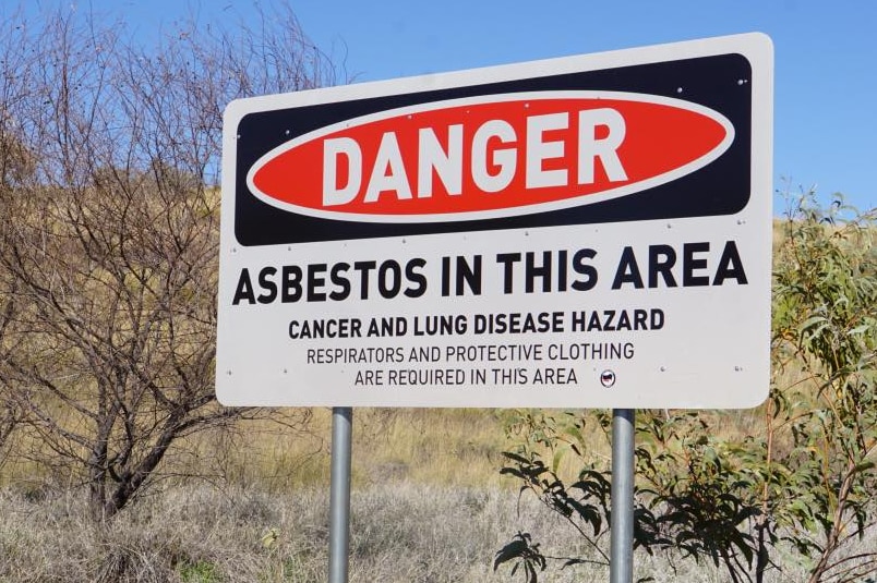 A sign in Wittenoom warning of health risks. trees in background
