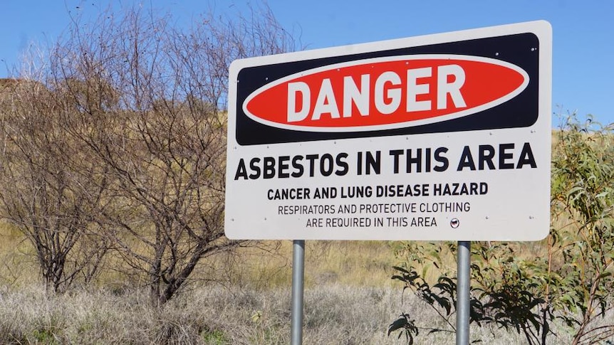 A sign in Wittenoom warning of health risks. trees in background