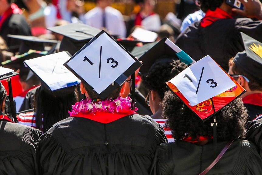 Students wearing graduation caps that say "1/3".