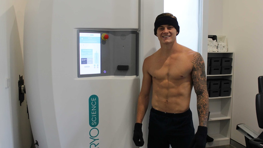 Cory Still smiles in front of the cryotherapy chamber.