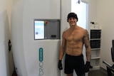 Cory Still smiles in front of the cryotherapy chamber.