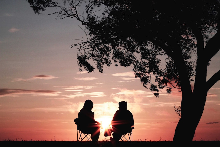 Couple sitting on chairs at sunset