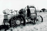 A black and white photo of an old tractor in a field.