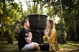 Photo of Autumn practicing yoga and meditation to treat her PTSD, she is sitting cross legged with a man, surrounded by trees.