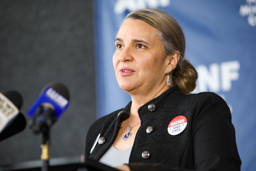 A woman wearing a black jacket with a badge that says 'ratios save lives' pinned to it. 