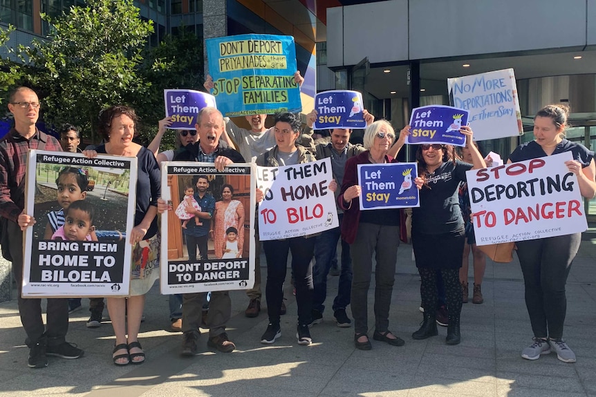 A group of 11 people holding placards calling for the Tamily family to be allowed to stay in Australia.