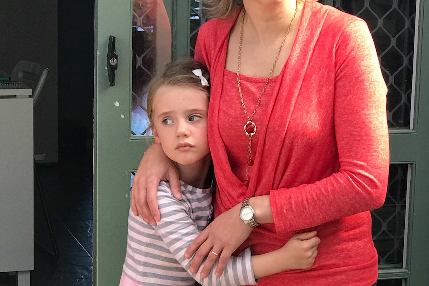 Maia Hood, 4, getting a cuddle from her mother at their front door.