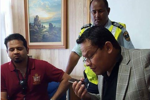 Former Nauru president Sprent Dabwido speaks into a phone as officials look on