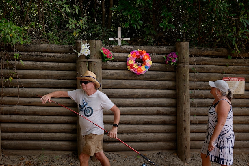 A fisherman holds is rod in front of a memorial at Cahill's Crossing.