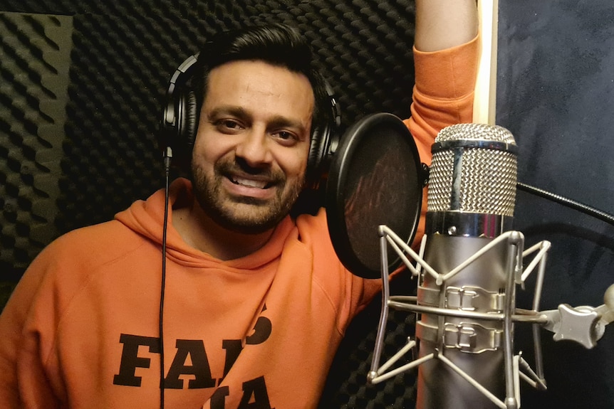 A man in a orange hoodie in front of a microphone