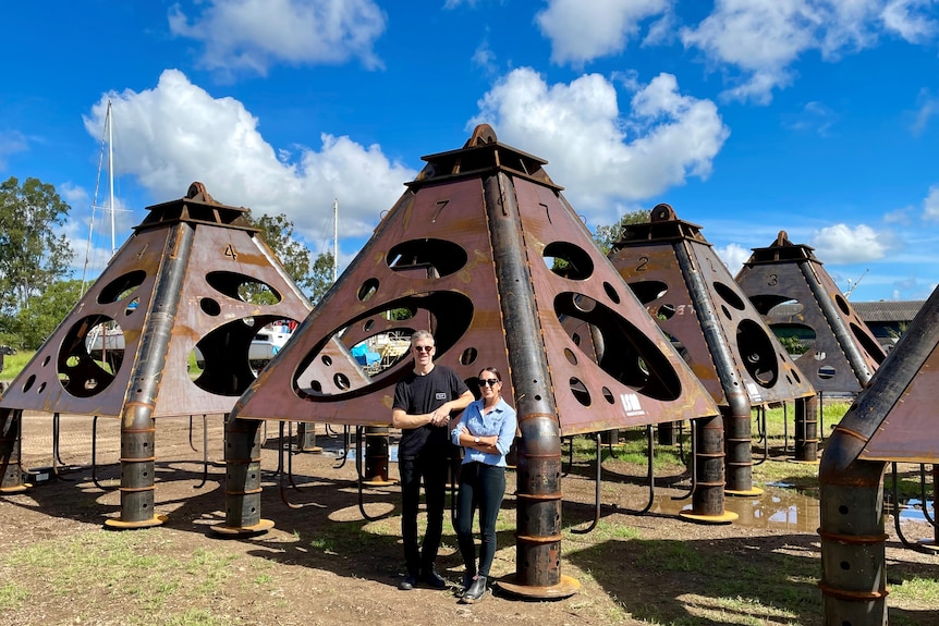 Two people standing in front metal structures