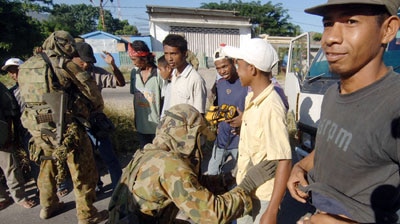 Australian soldiers check locals before they enter Dili at a check-point