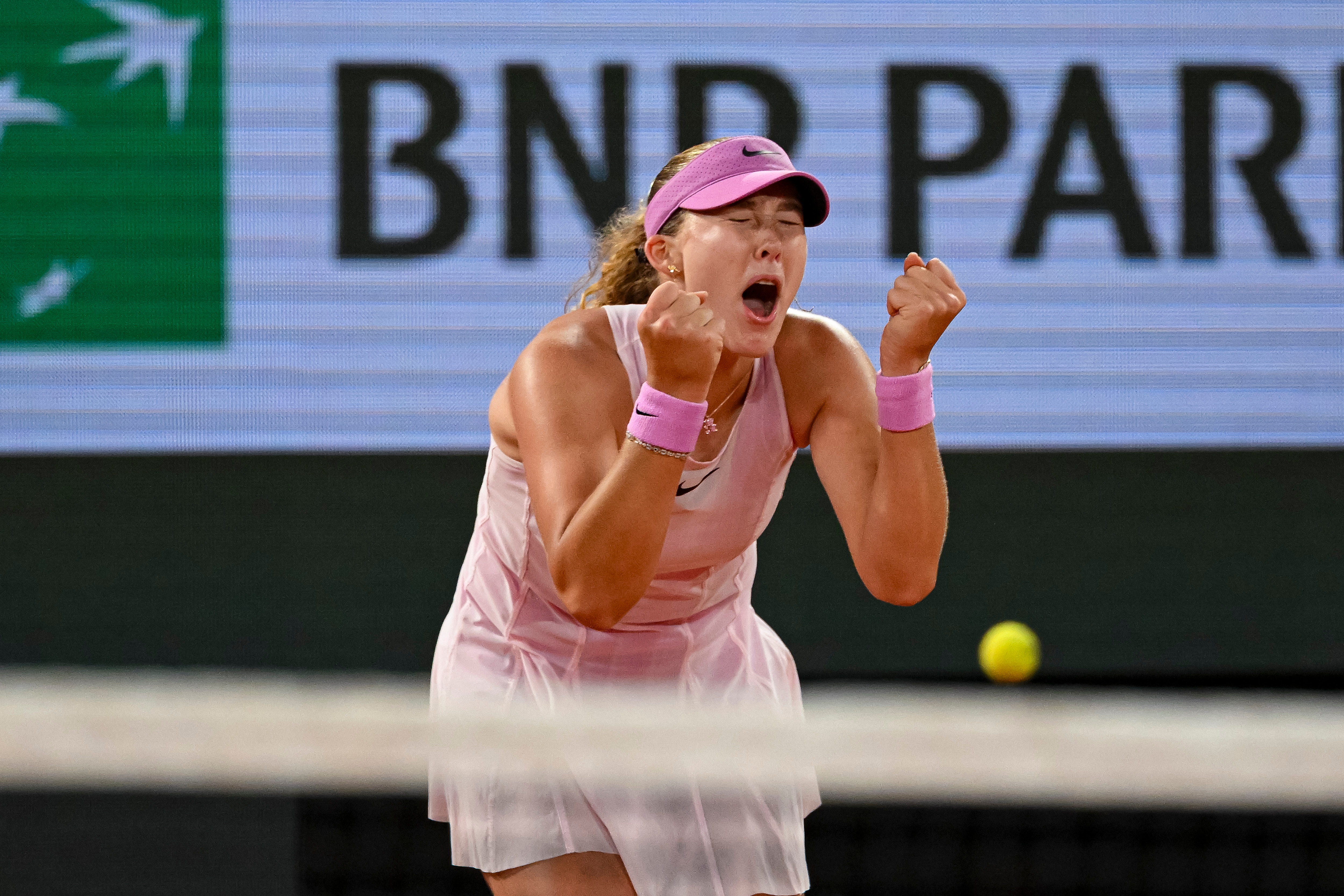 Mirra Andreeva clenches both fists and yells after winning at the French Open.