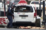 A Secret Service officer uses a mirror to check under a white passenger vehicle that struck a White House security barrier